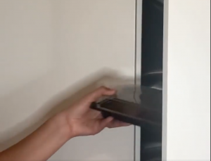 Hand placing tray into cupboard 